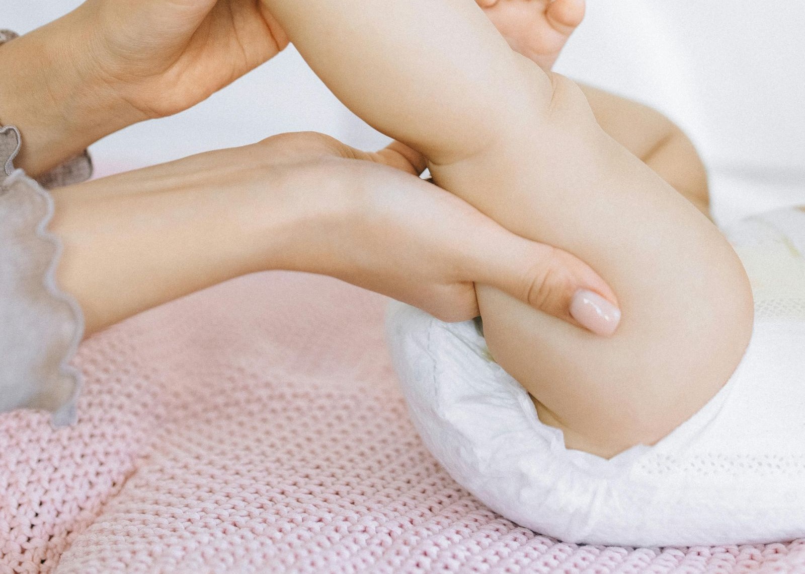 Mutter wickelt Baby und massiert Babybeine