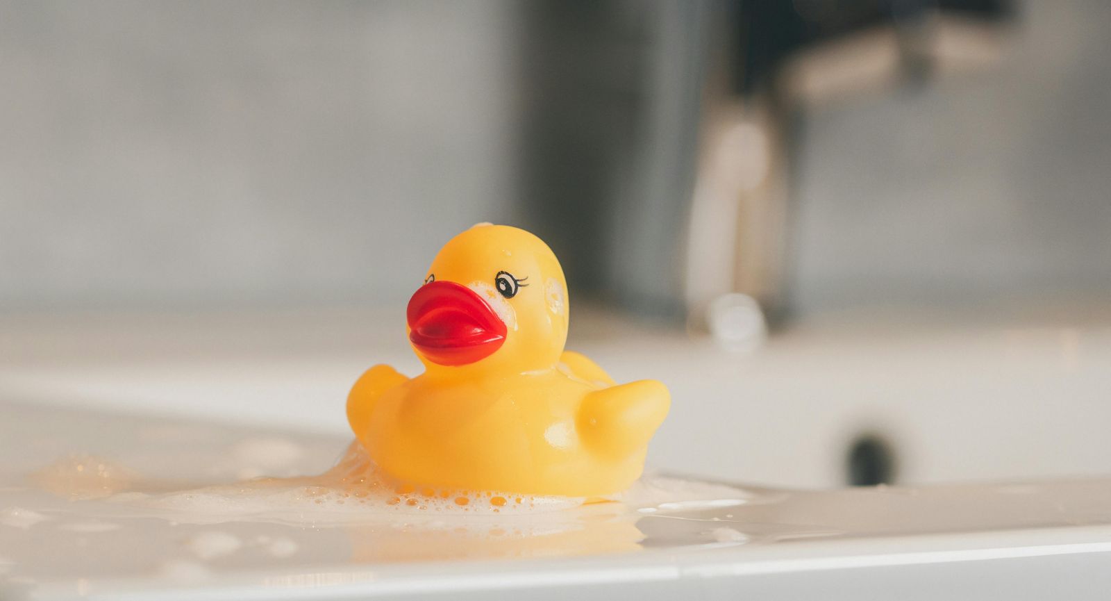 Badeente für Baby liegt auf Waschbecken