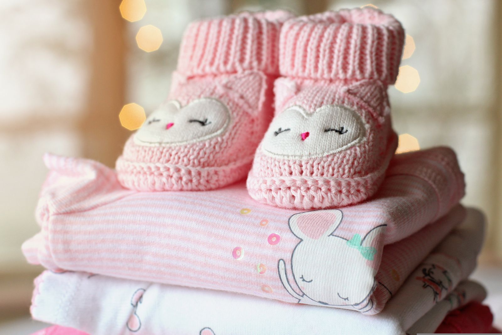 Babyschuhe und zusammengefaltete Strampler als Teil der Baby-Erstausstattung